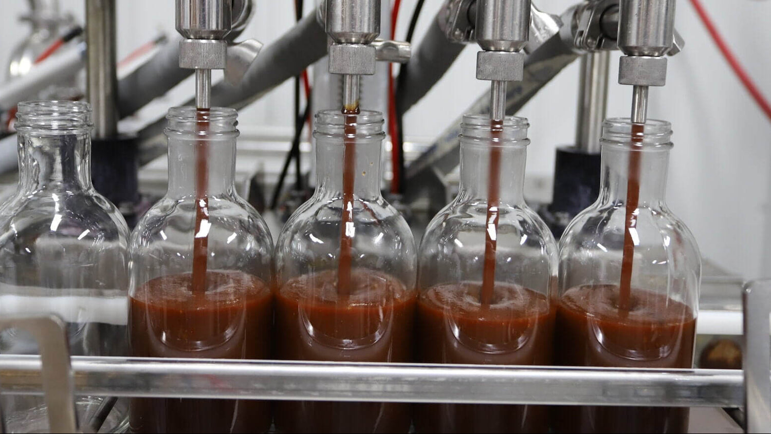 Bottles being filled with a dark liquid in an industrial setting