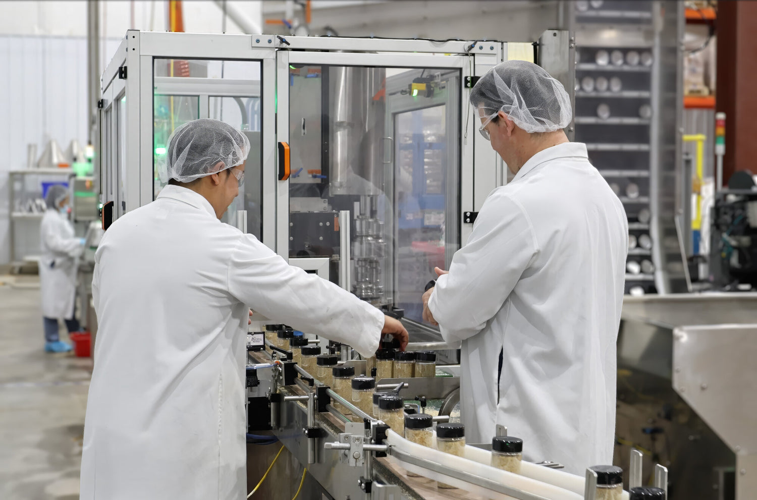 Two workers in a factory setting operating machinery.