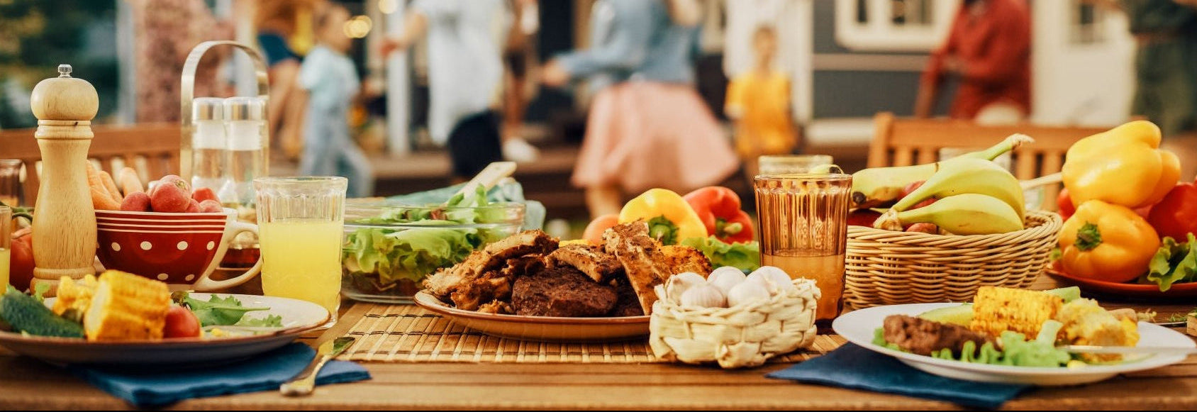 Outdoor gathering with a table full of food and people in the background.
